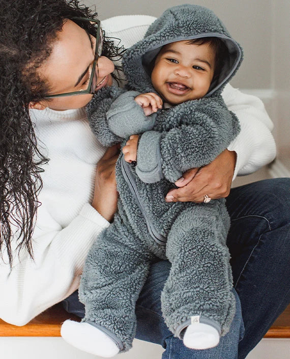 Baby boy wearing a grey fleece outfit with a parent