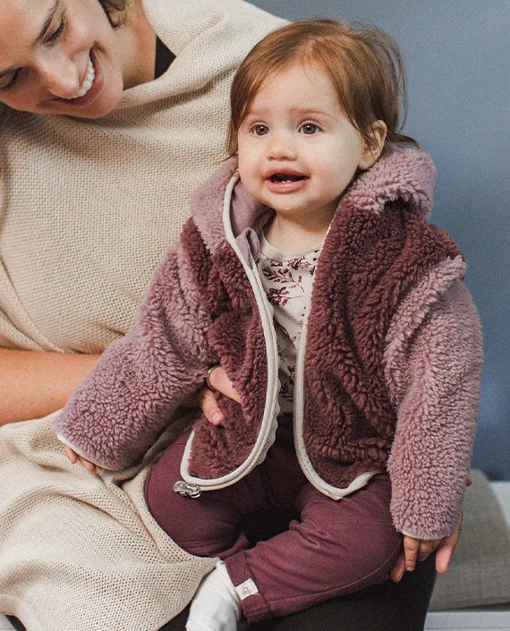 Baby girl wearing a mauve fleece outfit with a parent