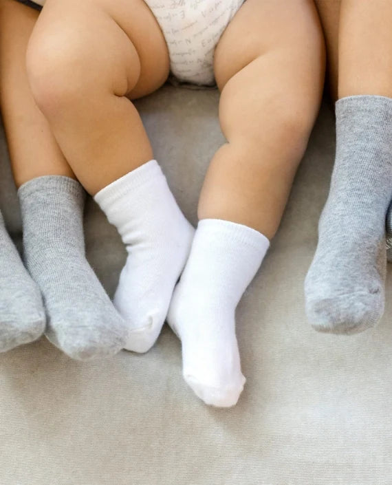 Baby legs wearing white and grey socks